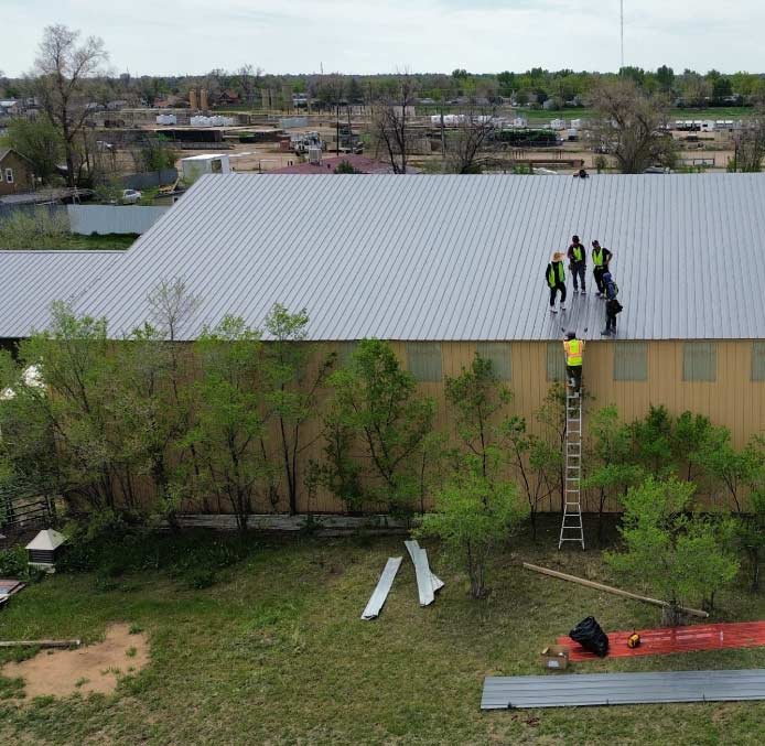 roofers-on-metal-roof Professional contractors inspecting a commercial metal roofing for damage and wear